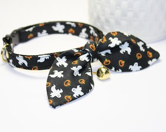 May include: Black cat collar with a bow tie featuring a white ghost and orange pumpkin pattern. The collar has a gold bell.
