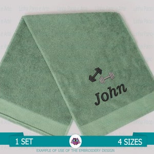 May include: Two green towels with a black dumbbell and the name John embroidered on one of the towels. The towels are folded and displayed on a white background.