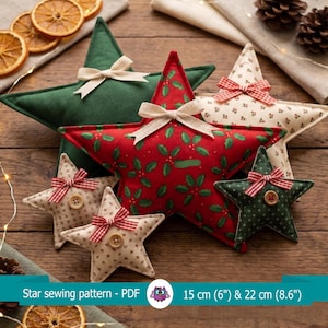 Pode incluir: Uma coleção de cinco ornamentos de estrela em tecido de vários tamanhos e padrões, incluindo verde sólido, estampa de azevinho vermelho e estampas florais creme. Cada estrela apresenta um pequeno laço de tecido ou um botão de madeira. Texto: Star sewing pattern - PDF 15 cm (6") & 22 cm (8.6").