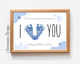 May include: A white framed print with blue baby footprints in the shape of a heart. The print says "From the top of my head to the tips of my toes! I YOU Happy Father's Day".