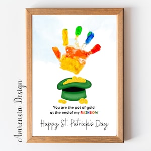 Può includere: Un'impronta di mano colorata a forma di arcobaleno con un cappello da folletto verde e monete d'oro in fondo. Il testo recita "You are the pot of gold at the end of my RAINBOW Happy St. Patrick's Day".