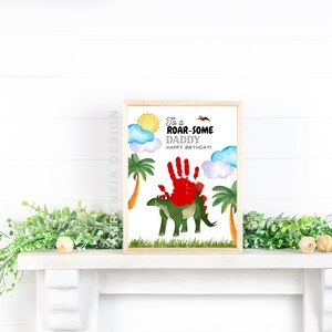 Puede incluir: Una tarjeta imprimible con un dinosaurio verde y una huella de mano roja. La tarjeta dice "To a Roar-some Daddy Happy Birthday!"