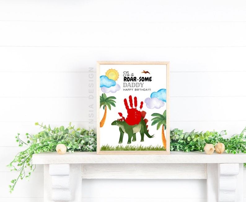 Puede incluir: Una tarjeta imprimible con un dinosaurio verde y una huella de mano roja. La tarjeta dice "To a Roar-some Daddy Happy Birthday!"