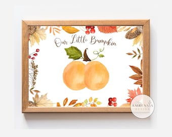 May include: A framed watercolour print displaying two orange pumpkins with green vines and the text "Our Little Bumpkin." The print is framed by a border of autumn leaves, berries, and pine cones, set against a white background.
