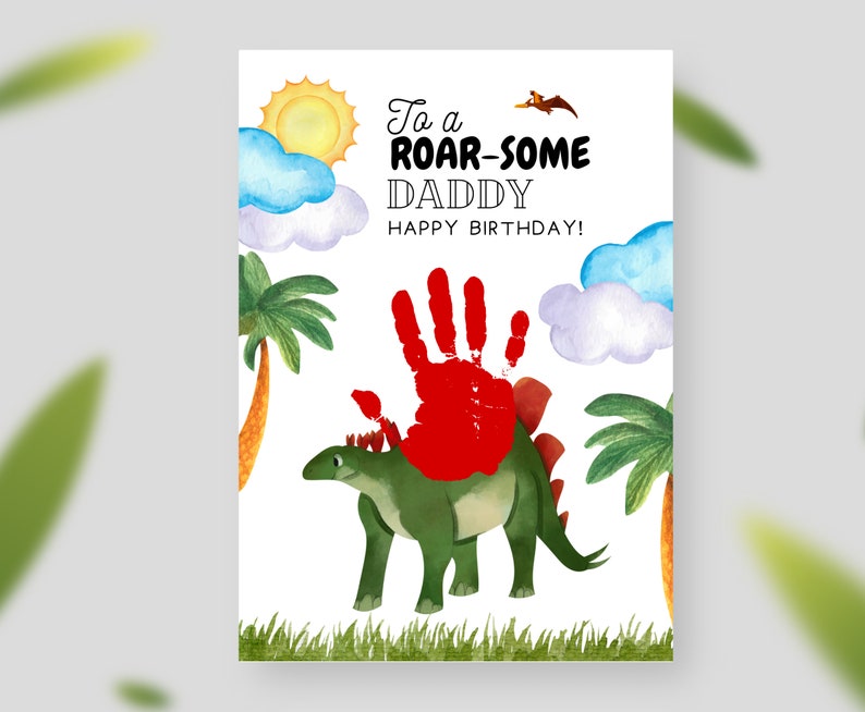 Puede incluir: Una tarjeta de cumplea&ntilde;os con un dinosaurio verde y una huella de mano roja. La tarjeta dice "To a Roar-some Daddy Happy Birthday!"