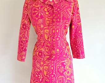 May include: A pink and orange dress with a geometric pattern. The dress has a collar and long sleeves.