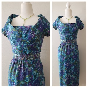 May include: A vintage floral print dress with a square neckline, short sleeves, and a fitted silhouette. The dress has a belt at the waist and a blue and purple floral pattern.
