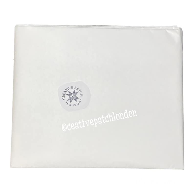 May include: A rectangular sheet of white tissue paper folded neatly. A circular sticker is affixed to the surface, featuring a star-like emblem and the text CREATIVE PATCH LONDON. The text @ceativepatchlondon is printed in white on the paper.