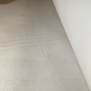 May include: A roll of translucent white paper featuring faint, thin blue grid lines printed across the surface. The paper is partially unrolled, showing a smooth texture and a light, semi-transparent quality that reveals subtle geometric patterns.