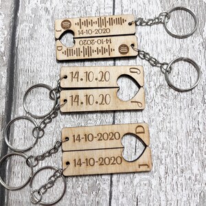 May include: Two wooden keyrings with a heart cut out, each engraved with the date 14-10-2020. One keyring has a barcode and the letters J and D on it. The other keyring has the letters J and D on it.