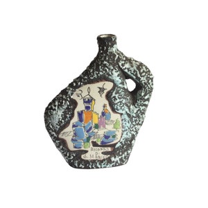 May include: A brown ceramic vase with a textured surface and a white glaze. The vase has a unique shape with a handle and a small opening at the top. It features a painted scene of a castle with colorful details and the text "RICORDO DI S. MARINO".
