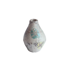 Puede incluir: Un pequeño jarrón de cerámica blanca con una superficie texturizada y un diseño de estrellas verdes y amarillas.