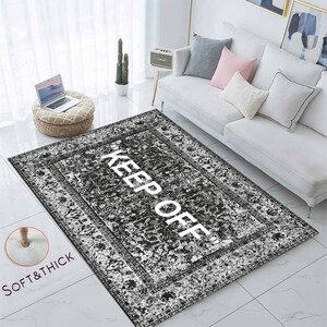May include: Black and white area rug with a vintage pattern and the text "KEEP OFF!" printed in white. The rug is soft and thick.