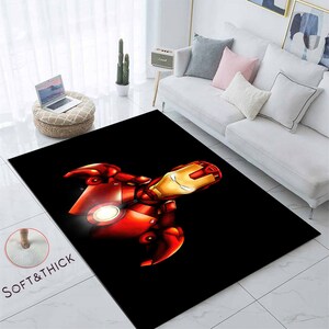 May include: A black area rug with a red and gold Iron Man illustration. The rug is soft and thick.