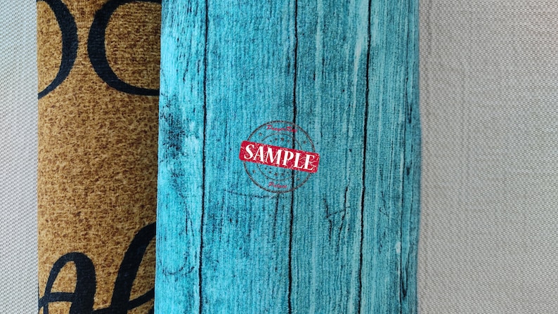 May include: Two doormats side by side. The left doormat is brown with black lettering that says "Welcome". The right doormat is blue with a wood grain pattern and a red stamp that says "SAMPLE".