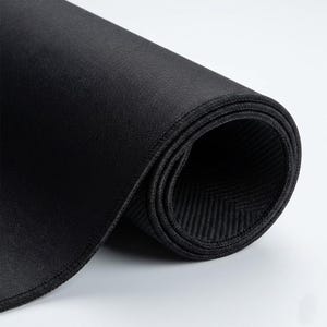 K&ouml;nnte beinhalten: Aufgerollte schwarze Mausunterlage mit einer gen&auml;hten Kante. Die Oberfl&auml;che ist glatt, w&auml;hrend die Unterseite ein strukturiertes Fischgr&auml;tenmuster aufweist. Das Pad besteht aus einem flexiblen Material.