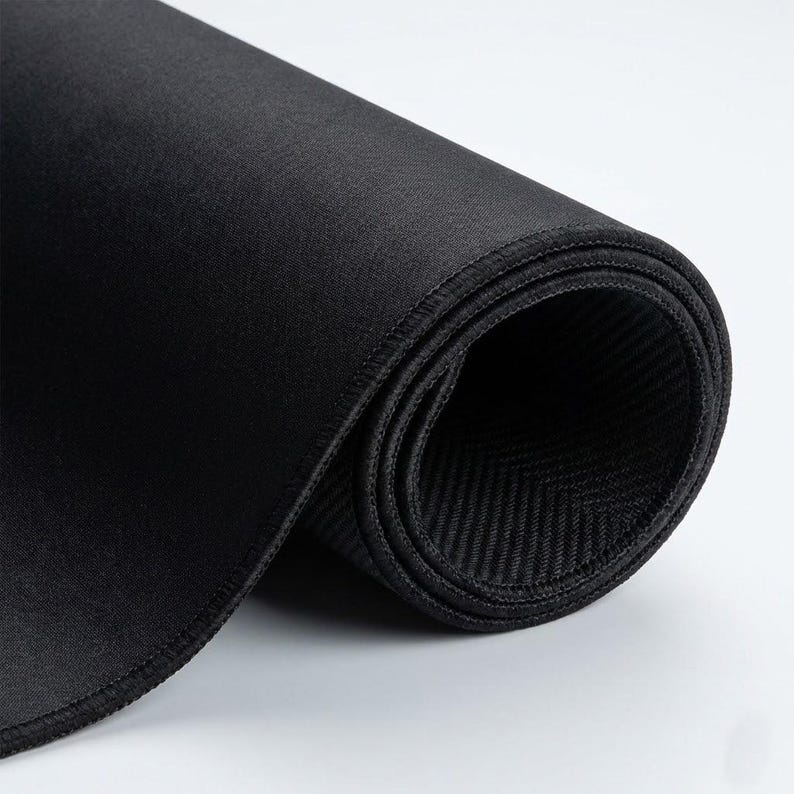 K&ouml;nnte beinhalten: Aufgerollte schwarze Mausunterlage mit einer gen&auml;hten Kante. Die Oberfl&auml;che ist glatt, w&auml;hrend die Unterseite ein strukturiertes Fischgr&auml;tenmuster aufweist. Das Pad besteht aus einem flexiblen Material.