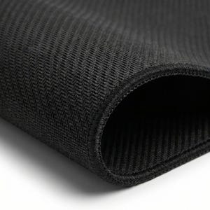 K&ouml;nnte beinhalten: Nahaufnahme eines schwarzen, strukturierten Stoffes mit einem gewebten Fischgr&auml;tmuster. Der Rand ist sauber mit einer gen&auml;hten Bord&uuml;re versehen. Der Stoff ist gefaltet und gibt einen dunklen Innenraum frei.