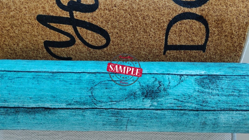 May include: A rolled up turquoise blue doormat with a wood grain pattern. The doormat is rolled up and the top of the roll is visible. The doormat is a sample.