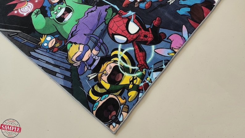 May include: A vibrant comic book print showcasing superheroes like Spider-Man and Hulk. The design is on a square piece of fabric with a grey border. The image is a close-up of a corner of the fabric.