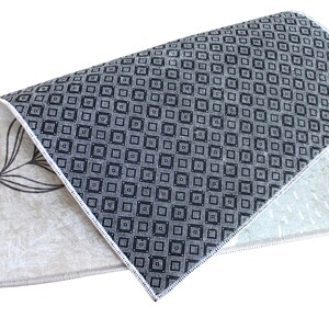 May include: A folded rug with a black and white geometric pattern on one side and a beige floral pattern on the other side.