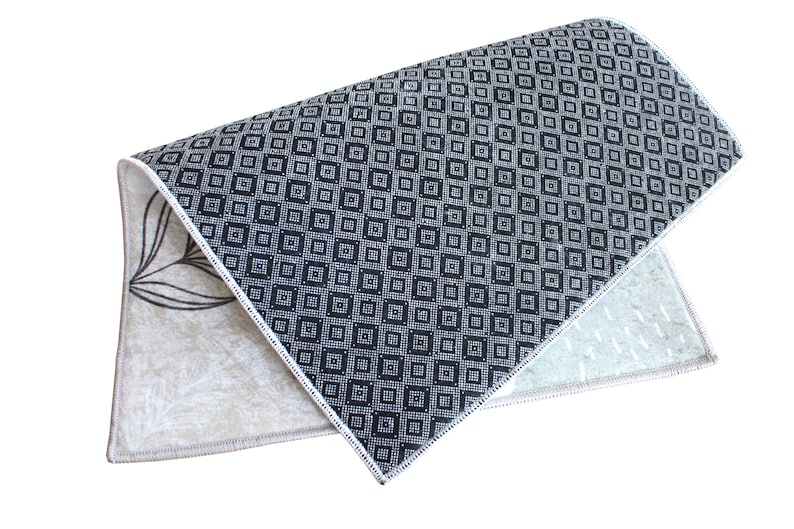 May include: A folded rug with a black and white geometric pattern on one side and a beige floral pattern on the other side.