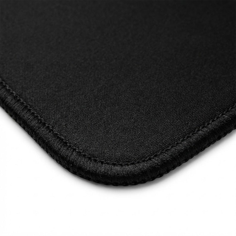 K&ouml;nnte beinhalten: Nahaufnahme eines schwarzen Stoffes mit abgerundeter Ecke. Der Stoff hat eine strukturierte Oberfl&auml;che und ist mit einer gen&auml;hten Bord&uuml;re eingefasst. Das Bild ist vor einem wei&szlig;en Hintergrund.