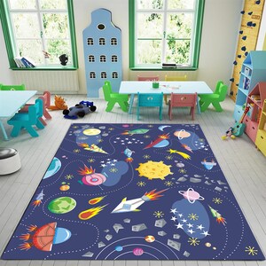 May include: A blue and white space-themed rug with rockets, planets, stars, and comets. The rug is perfect for a child's playroom or bedroom.