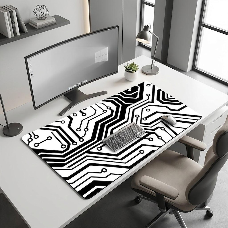 K&ouml;nnte beinhalten: Schwarzes und wei&szlig;es Computer-Mauspad mit Leiterplatten-Design. Das rechteckige Pad hat ein sich wiederholendes Muster aus schwarzen Linien und Formen auf wei&szlig;em Hintergrund. Eine Tastatur und eine Maus liegen auf dem Pad, neben einem Computermonitor.