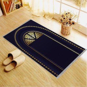 May include: A navy blue prayer rug with a gold geometric design and border. The rug features a central arched design with a gold lattice pattern. Two beige slippers are next to the rug on a wooden floor.