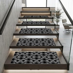 May include: A modern staircase with wooden steps, each fitted with a geometric patterned stair tread in shades of grey and black. The treads have a repeating interwoven design. Recessed lighting illuminates the steps, enhancing the contemporary feel.