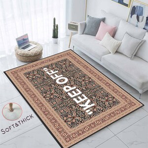 May include: A black and beige patterned rug with a white "KEEP OFF" text in the centre. The rug has a soft and thick texture.