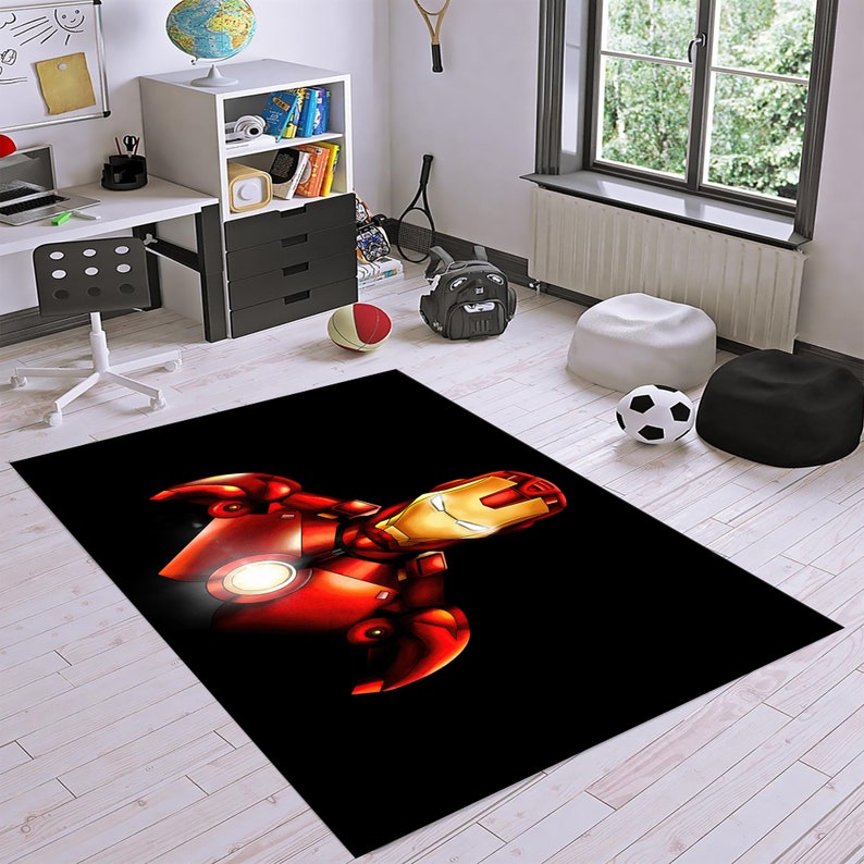 May include: A black and red area rug with a cartoon image of Iron Man's head and shoulders. The rug is on a light wood floor.