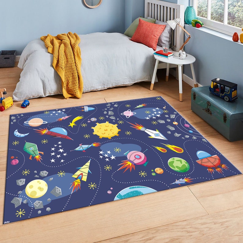 May include: A blue space-themed rug with rockets, planets, stars, and comets. The rug is perfect for a child's bedroom or playroom.