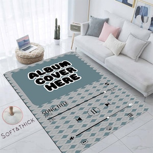 May include: A blue and grey rug with a music player design. The rug has a white diamond pattern and the text "ALBUM COVER HERE" in black. The rug also has a song title, artist, and time stamp.