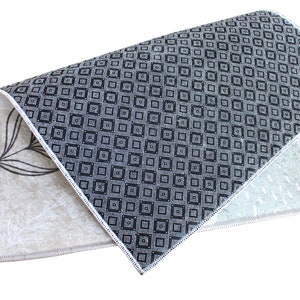 May include: A folded rug with a black and white geometric pattern on one side and a beige floral pattern on the other side.