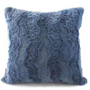 May include: A soft, blue faux fur throw pillow with a wavy pattern. The pillow is square shaped and has a subtle sheen.