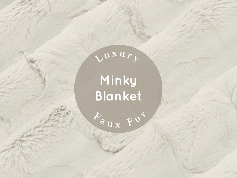 Pu&ograve; includere: Primo piano di una morbida coperta in pelliccia sintetica bianca. La coperta &egrave; testurizzata e soffice, con un'etichetta circolare che recita "Luxury Minky Blanket Faux Fur".