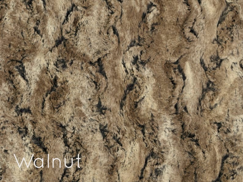 K&ouml;nnte beinhalten: Nahaufnahme eines Kunstpelzes in Walnussfarbe. Der Stoff hat eine weiche, flauschige Textur mit einem marmorierten Muster in Braun und Schwarz.
