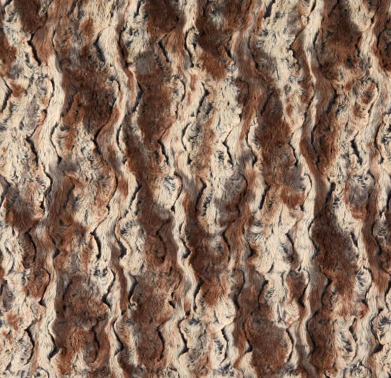 May include: A brown, gray, and white faux fur fabric with a wavy pattern.