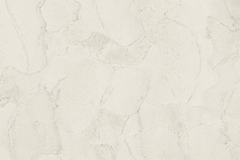 Pu&ograve; includere: Tessuto in pelliccia sintetica bianca con una texture morbida e soffice. Il tessuto presenta un motivo sottile di protuberanze e creste rialzate.