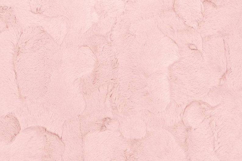 May include: A soft, plush fabric in a pale pink color. The fabric has a fuzzy texture and a subtle pattern.