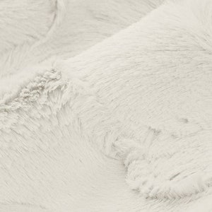 Pu&ograve; includere: Primo piano di un tessuto in pelliccia sintetica bianca e morbida. Il tessuto ha una consistenza soffice e un leggero bagliore.