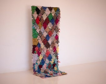 May include: A colorful, handwoven rug with a diamond pattern. The rug is made of recycled materials and has a unique, bohemian style.