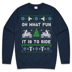 May include: Navy blue sweatshirt with a festive design. The design includes motorcycles, snowflakes, and a Christmas tree, with the text "OH WHAT FUN IT IS TO RIDE" in white and green. A perfect gift for motorcycle enthusiasts.