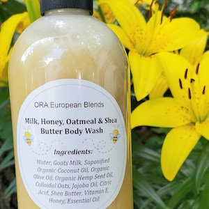 May include: A clear plastic bottle with a black lid filled with a yellow liquid. The bottle has a white label with the text "ORA European Blends Milk, Honey, Oatmeal & Shea Butter Body Wash" and a list of ingredients.