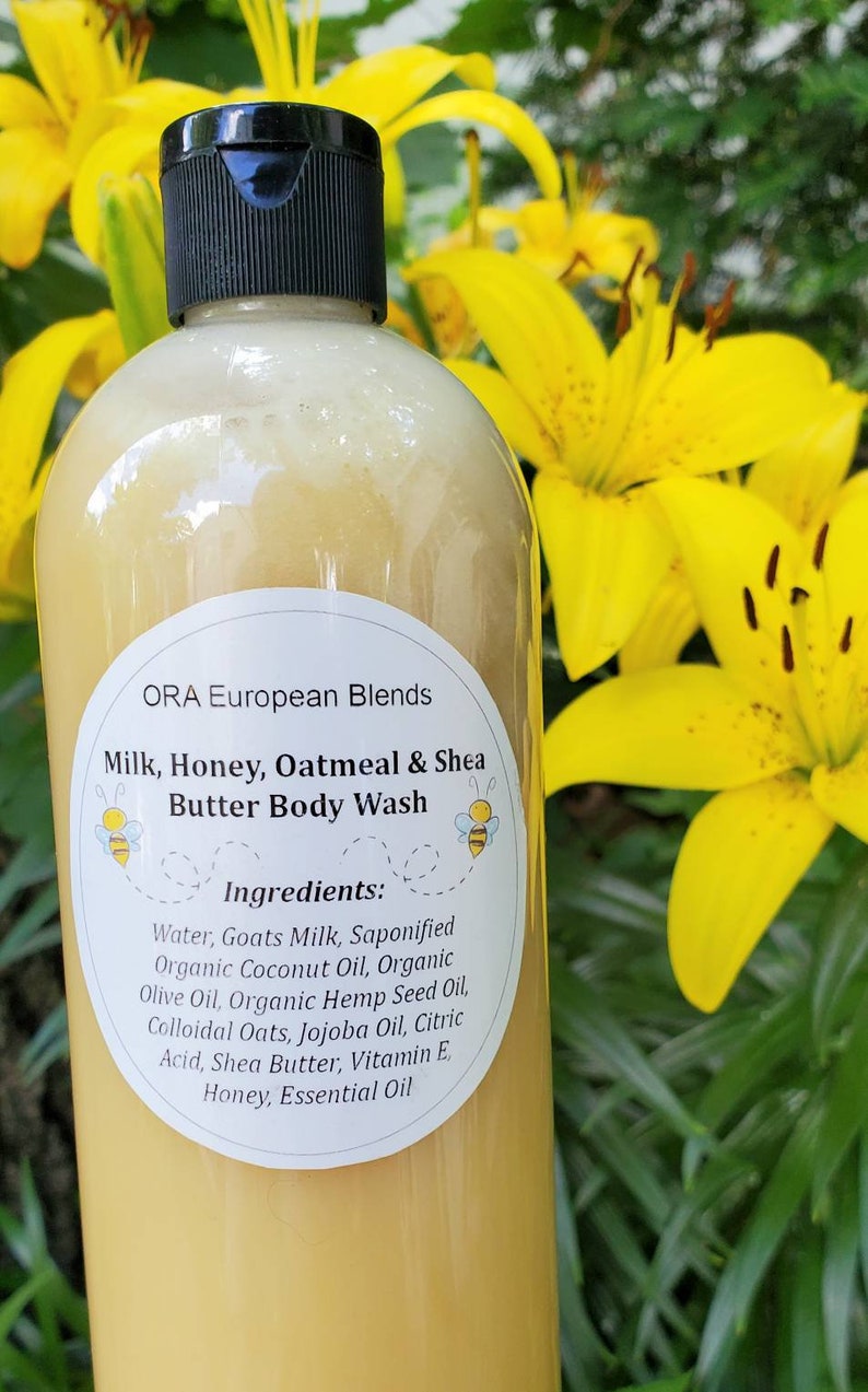 May include: A clear plastic bottle with a black lid filled with a yellow liquid. The bottle has a white label with the text "ORA European Blends Milk, Honey, Oatmeal & Shea Butter Body Wash" and a list of ingredients.
