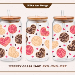 Puede incluir: Tres vasos de vidrio transparentes con tapas de bambú y pajitas. Cada vaso presenta un patrón repetido de pasteles en forma de corazón rosa y marrón con lunares blancos.