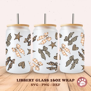 Op de afbeelding: Drie Libbey glazen wraps, elk met een bamboe deksel en een roestvrijstalen rietje. De wraps hebben een herhalend patroon van strikken, sterren en harten in zwart-wit geruite en luipaardprint ontwerpen. De tekst "LIBBERY GLASS 16OZ WRAP" is zichtbaar.