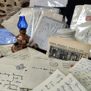 May include: A collection of vintage letters and postcards with handwritten notes, stamps, and a blue oil lamp. The letters are on aged paper with faded ink and include a stamp that reads "FORCES AIR MAIL". The postcard is from "MIRROR, THURSDAY, MARCH 6, 1947".